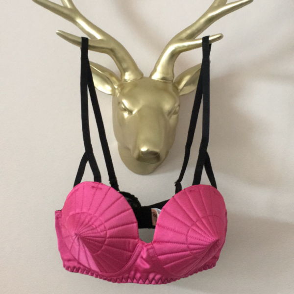 Gold wall mounted stag head with hot pink bullet bra on display