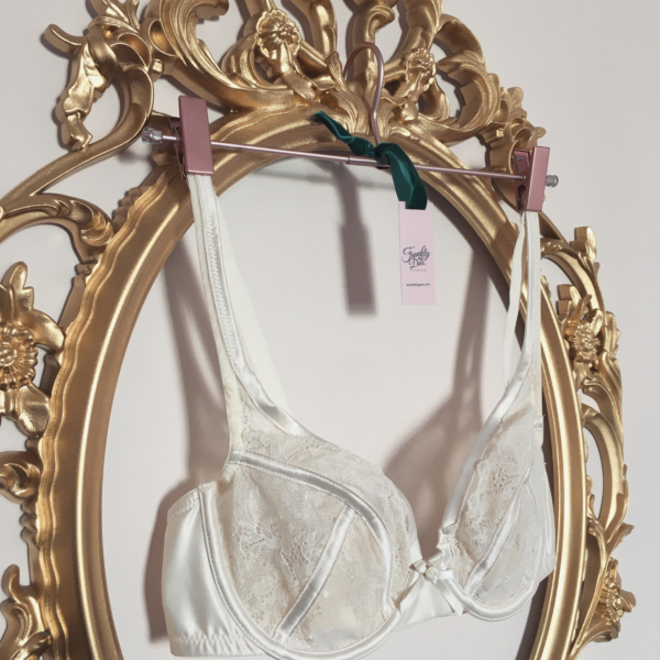 Oval baroque style gold frame with ivory satin bra hanging in centre